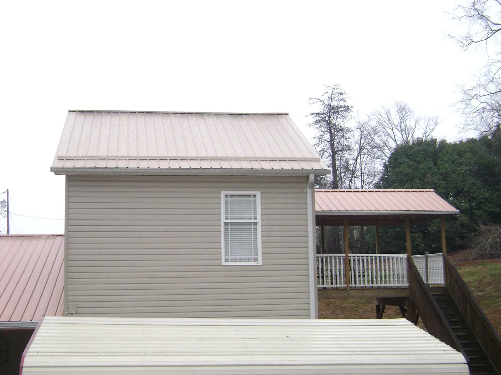 Tan metal roofs on a two story addition and attached porch, from a Roof Replacement job in Richfield